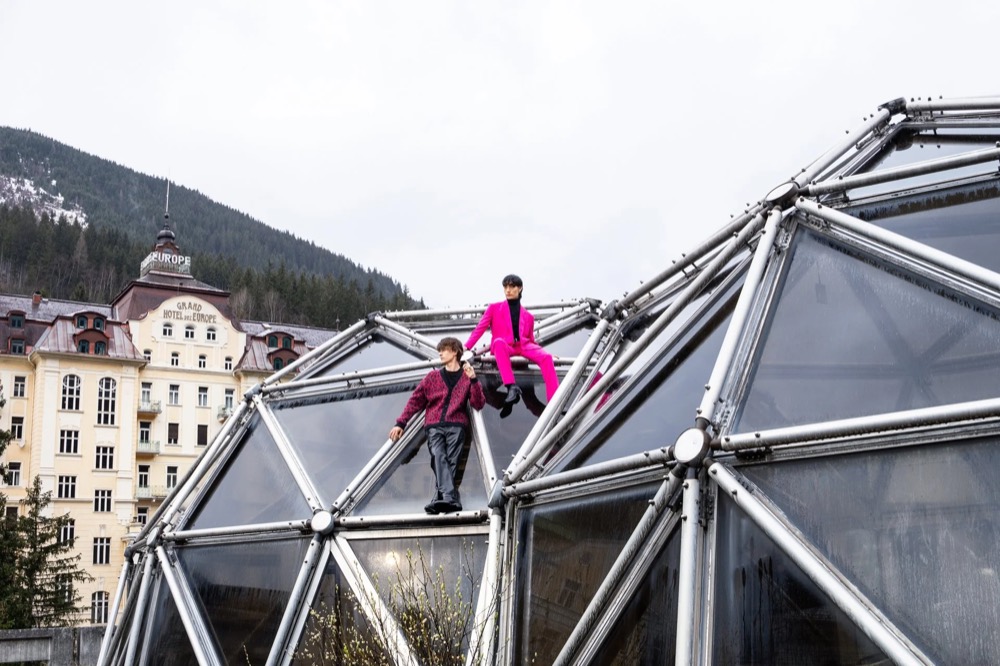 Model klettert auf eine geodätische Glaskuppel, Drykorn-Kampagne HW/AW 23 in Bad Gastein