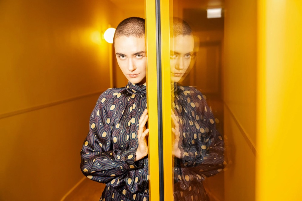 Model im karierten Anzug in einem gelb beleuchteten Aufzug, Drykorn-Kampagne HW/AW 23 in Bad Gastein
