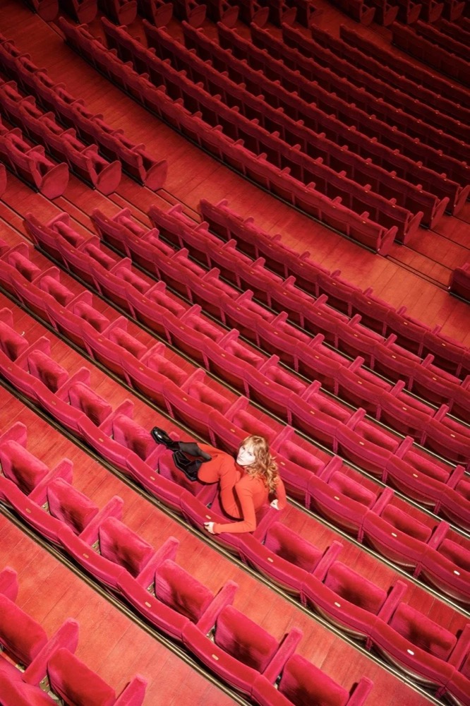 Model liegt zwischen roten Theatersesseln, von oben, Drykorn-Kampagne HW/AW 24 in einem Theater in Turin