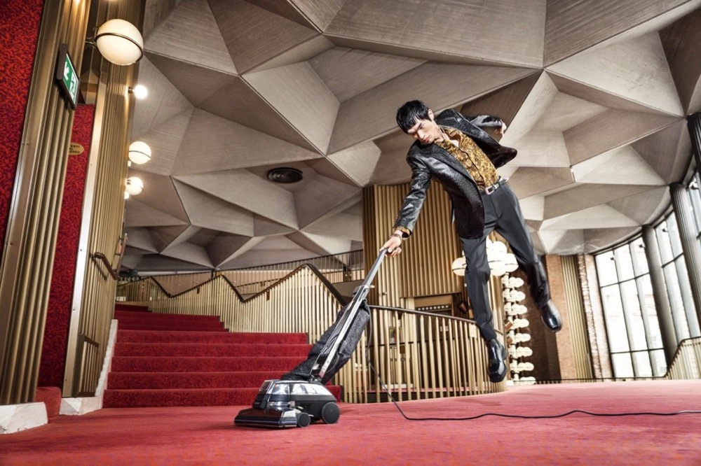 Model posiert auf einer Treppe in einem modernistischen Foyer, Drykorn-Kampagne HW/AW 24 in einem Theater in Turin