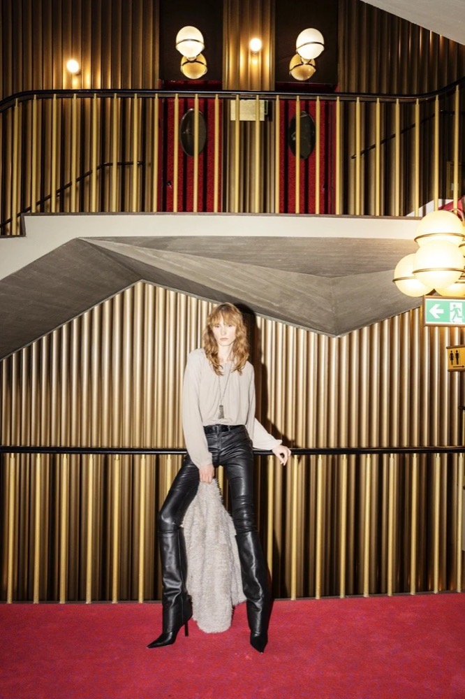 Model vor goldenen Wandpaneelen, Drykorn-Kampagne HW/AW 24 in einem Theater in Turin