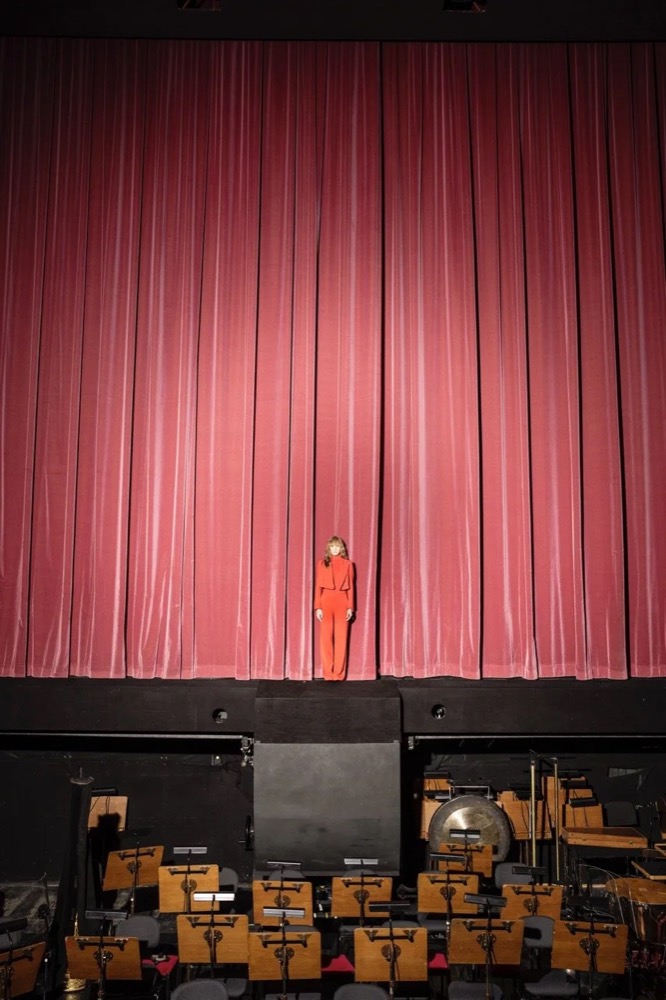Model auf der Bühne vor einem roten Vorhang, Drykorn-Kampagne HW/AW 24 in einem Theater in Turin