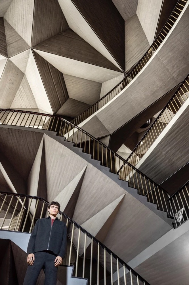 Model in einem modernistischen Foyer mit geometrischer Decke, Drykorn-Kampagne HW/AW 24 in einem Theater in Turin