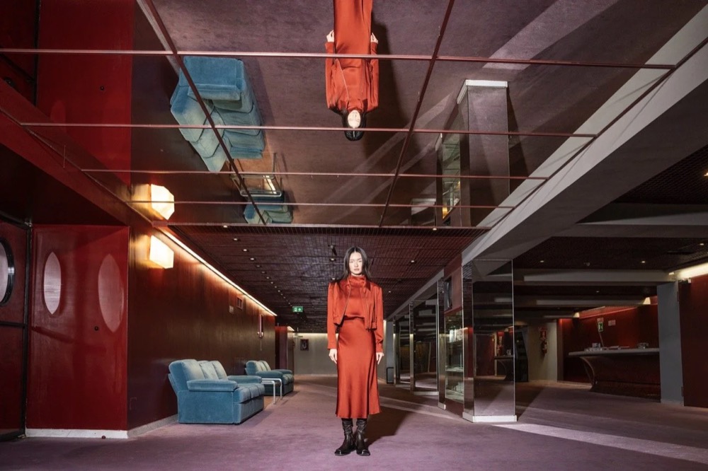 Model in Rot in einem langen Theaterflur, Drykorn-Kampagne HW/AW 24 in einem Theater in Turin