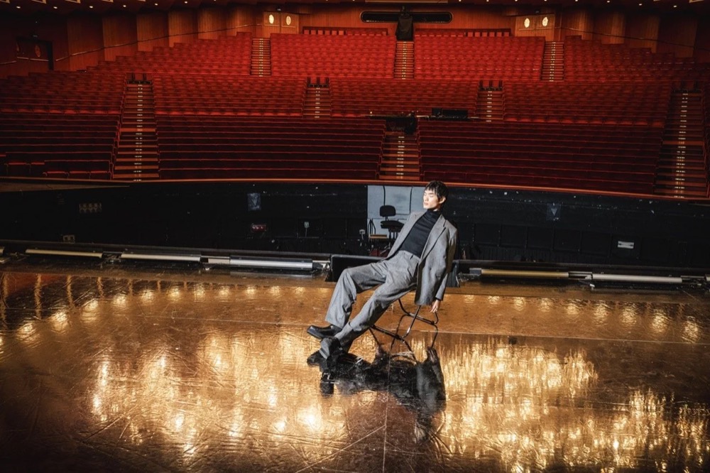 Model liegt auf glänzendem Boden unter Kronleuchtern, Drykorn-Kampagne HW/AW 24 in einem Theater in Turin