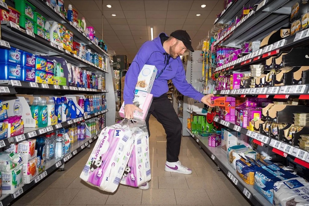 Mann mit pinkem Einkaufswagen in einem Supermarktgang, Bespoke-Shooting für ING