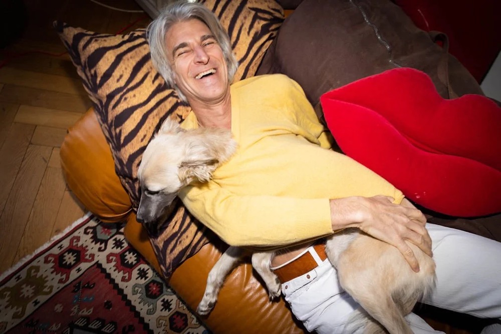 Mann im gelben Pullover entspannt mit seinem Hund auf dem Sofa, Bespoke-Shooting für ING