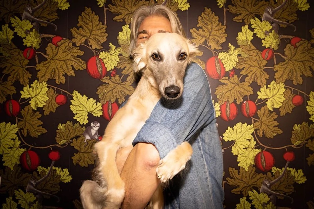 Person hält einen Hund vor einer geblümten Tapete, Bespoke-Shooting für ING