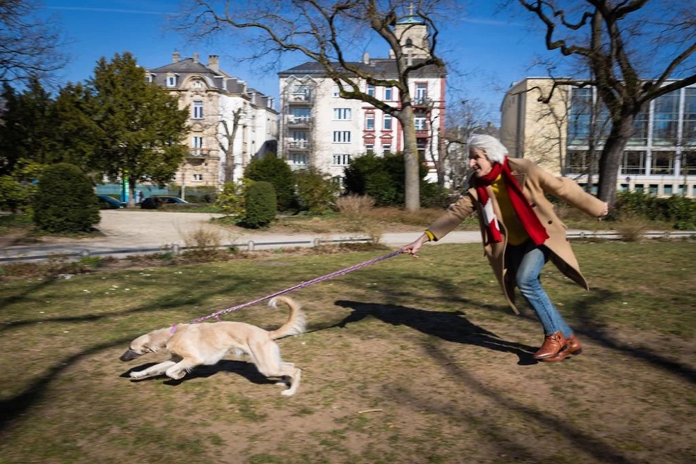 Frau und Hund spielen im Park, Bespoke-Shooting für ING