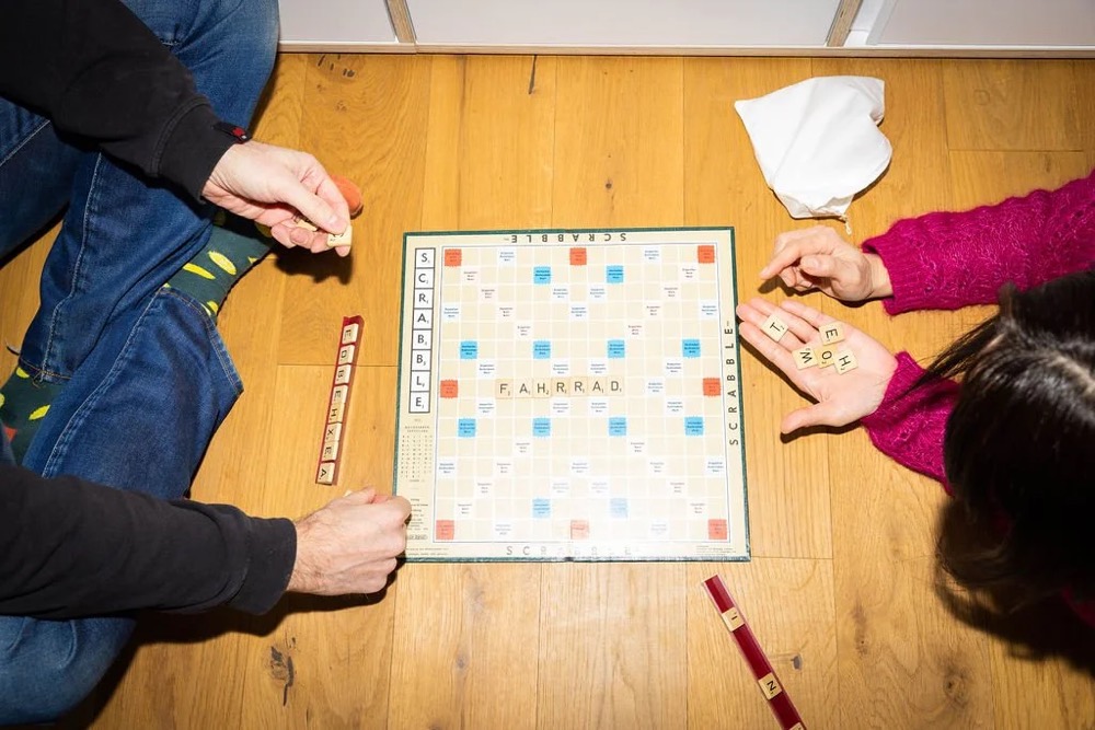 Menschen spielen ein Brettspiel an einem Holztisch, Bespoke-Shooting für ING