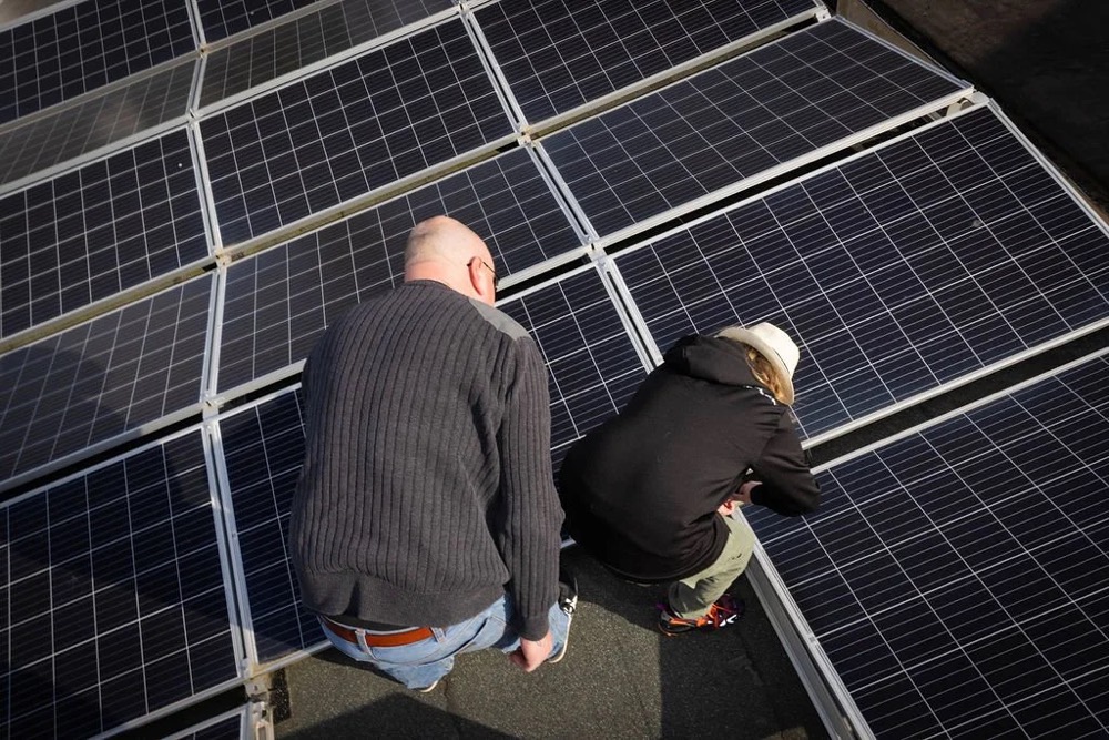 Zwei Männer prüfen Solarmodule auf einem Dach, Bespoke-Shooting für ING