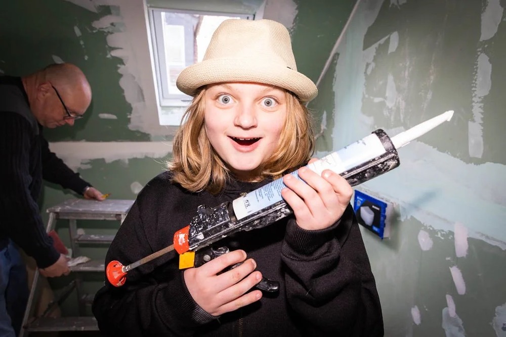 Kind mit Strohhut hält eine Kartuschenpistole, Bespoke-Shooting für ING