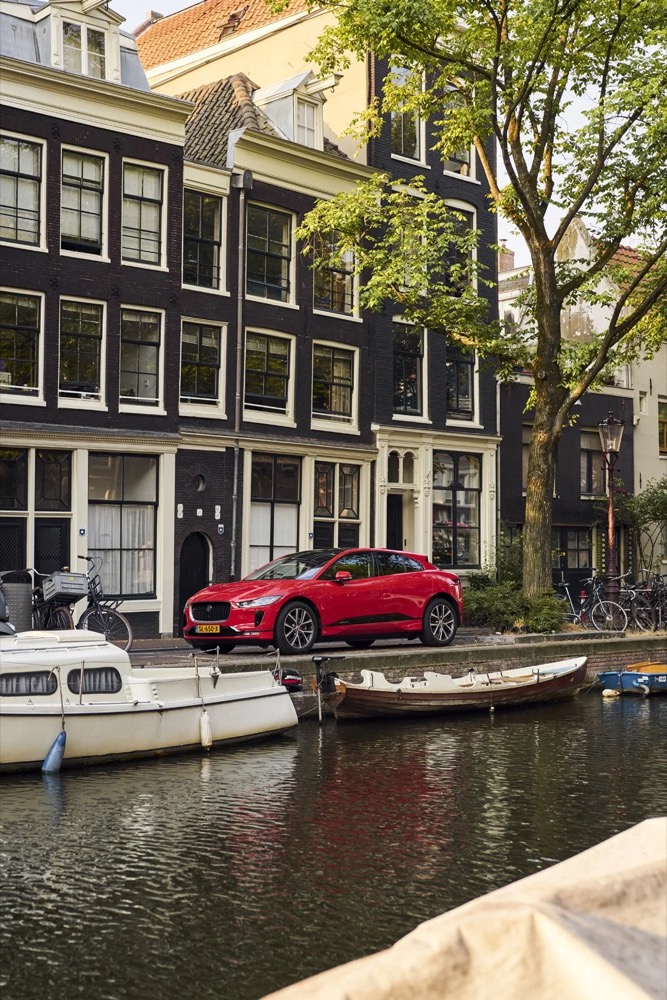 Roter Jaguar I-PACE an einer Amsterdamer Gracht mit Booten