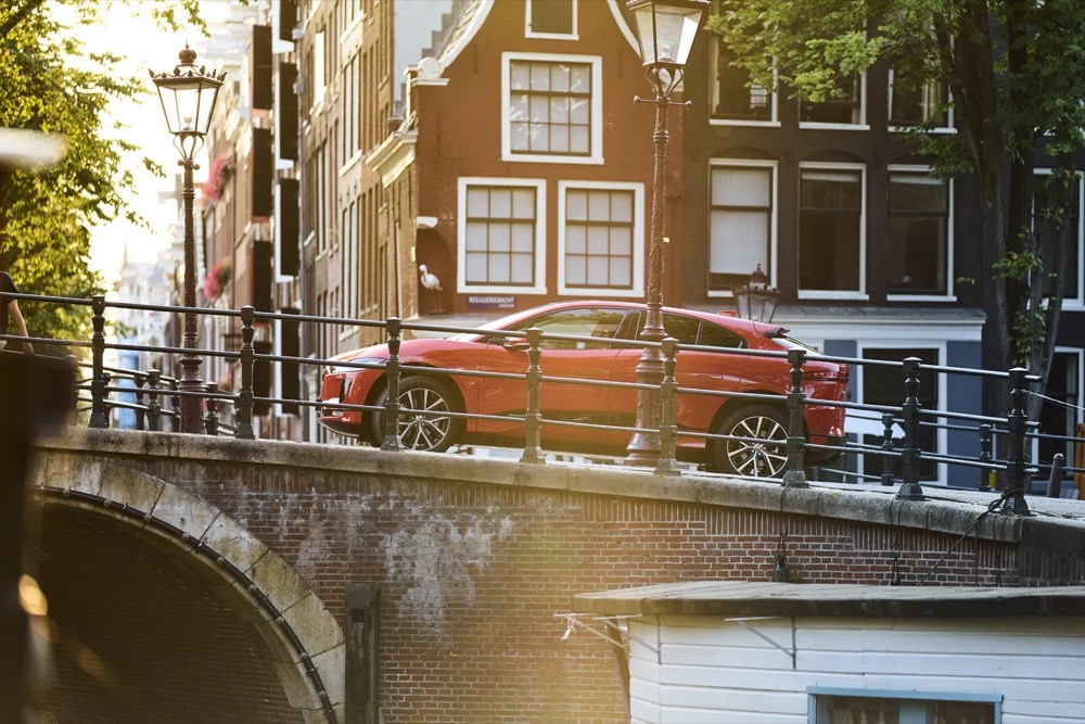 Roter Jaguar I-PACE fährt in Amsterdam über eine Grachtenbrücke