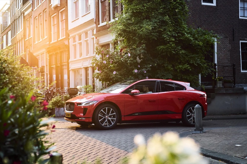 Roter Jaguar I-PACE fährt durch eine Amsterdamer Straße