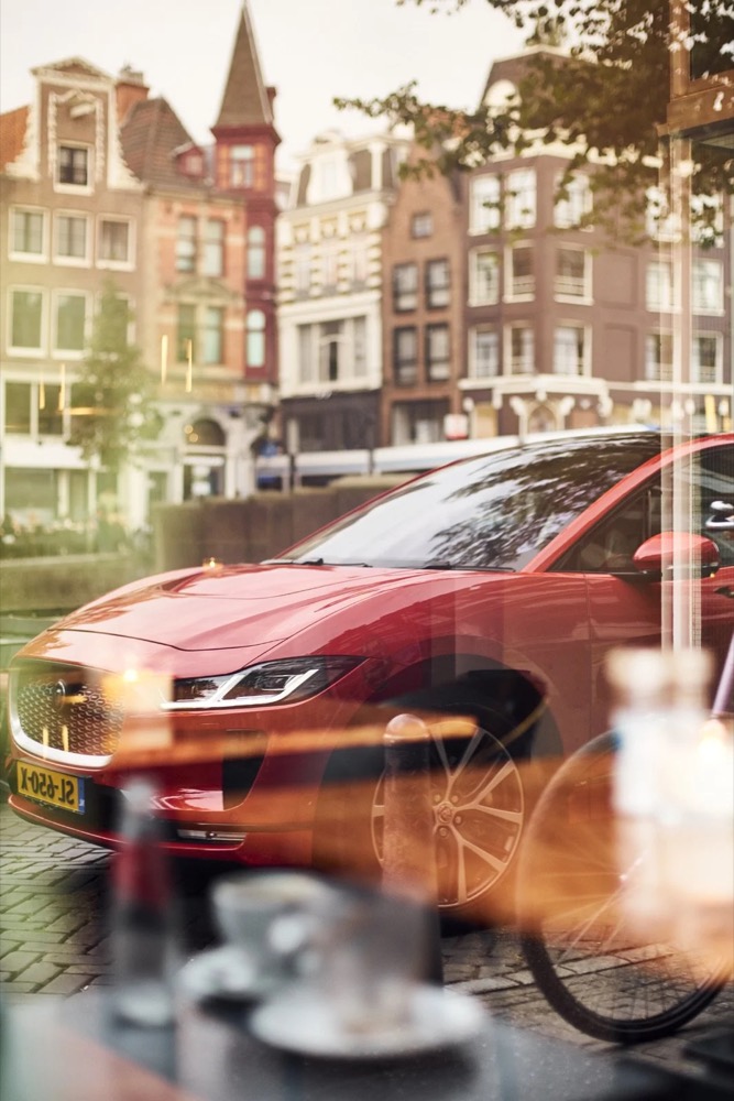 Roter Jaguar I-PACE, durch ein Café-Fenster in Amsterdam gesehen
