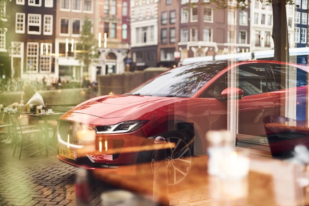 Roter Jaguar I-PACE spiegelt sich in einem Fenster an einer Amsterdamer Gracht