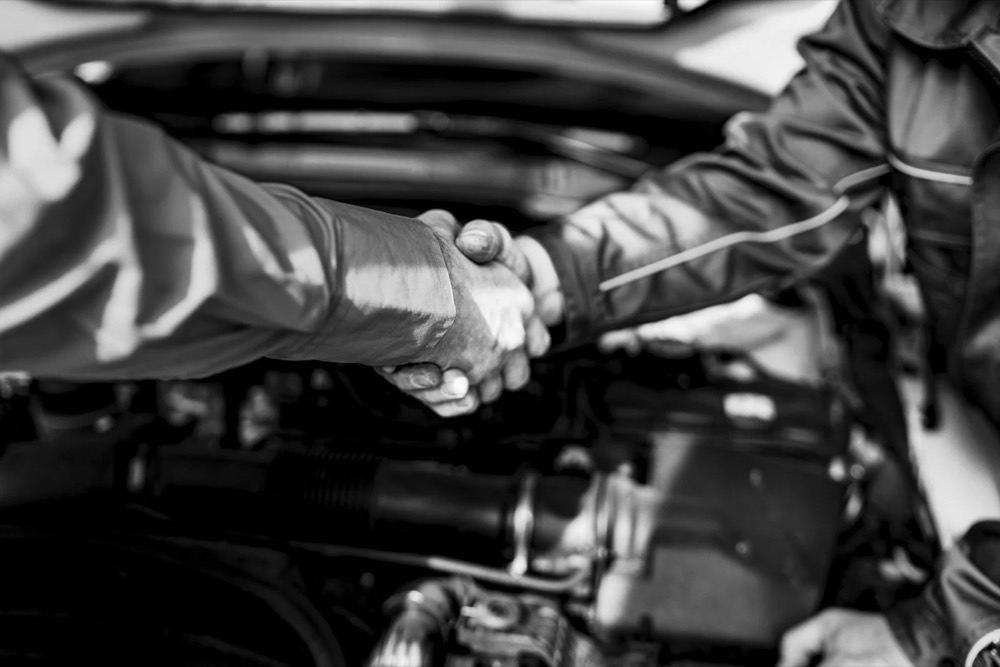 Handschlag über einem offenen Motorraum, Jaguar Land Rover Tradeparts