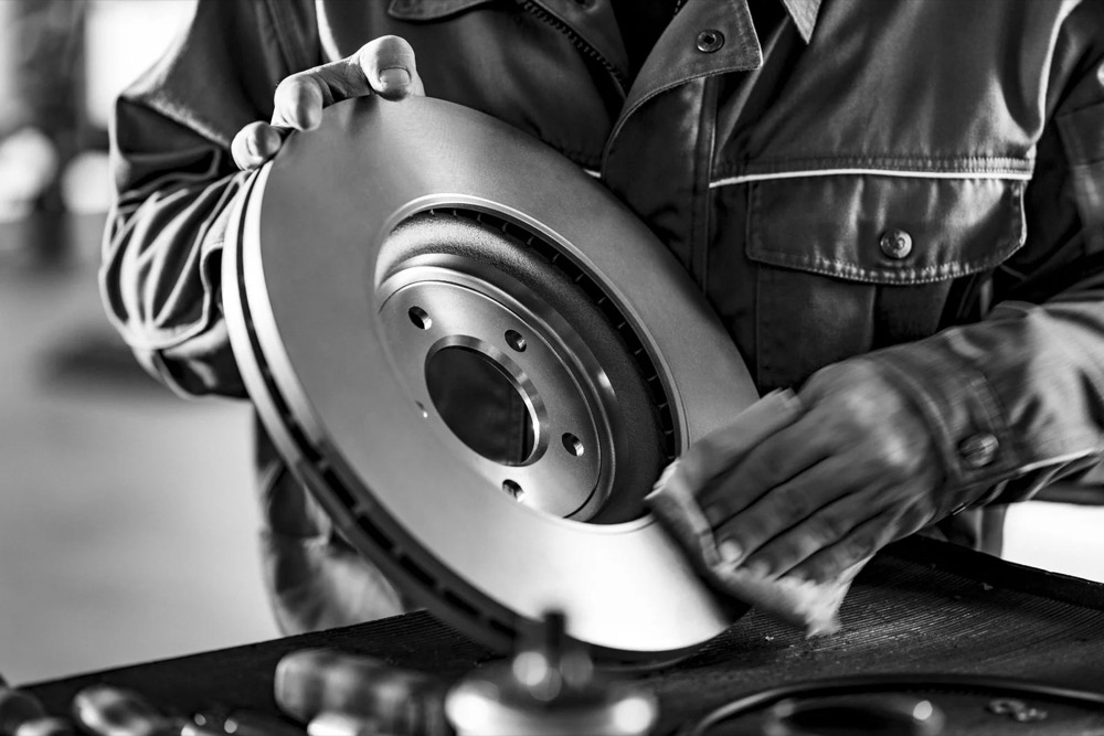 Mechaniker hält eine neue Bremsscheibe, Jaguar Land Rover Tradeparts