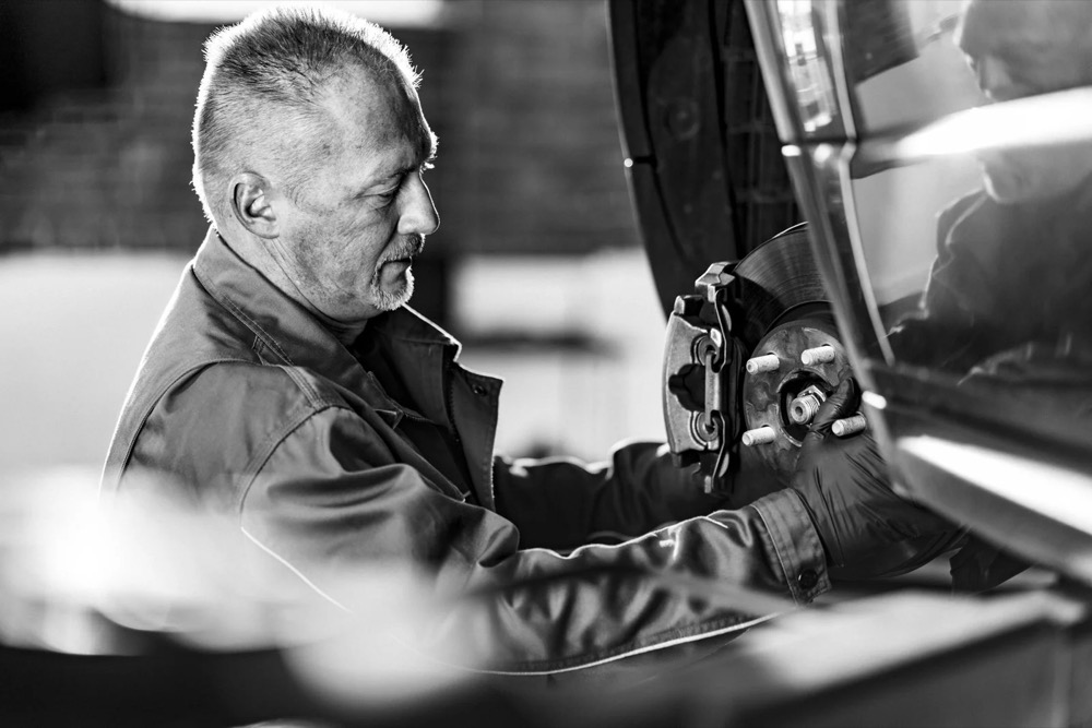 Mechaniker arbeitet in der Werkstatt an einem Rad, Jaguar Land Rover Tradeparts