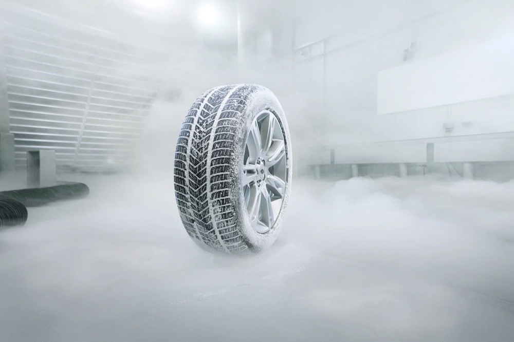 Winterreifen auf einer Alufelge in einer nebligen Werkstatt, Jaguar Land Rover Winterräder und -reifen