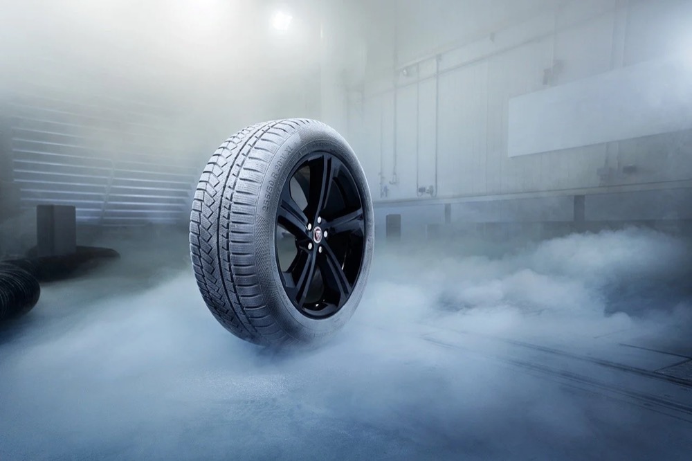 Winterreifen auf einer schwarzen Alufelge, umgeben von Nebel, Jaguar Land Rover Winterräder und -reifen