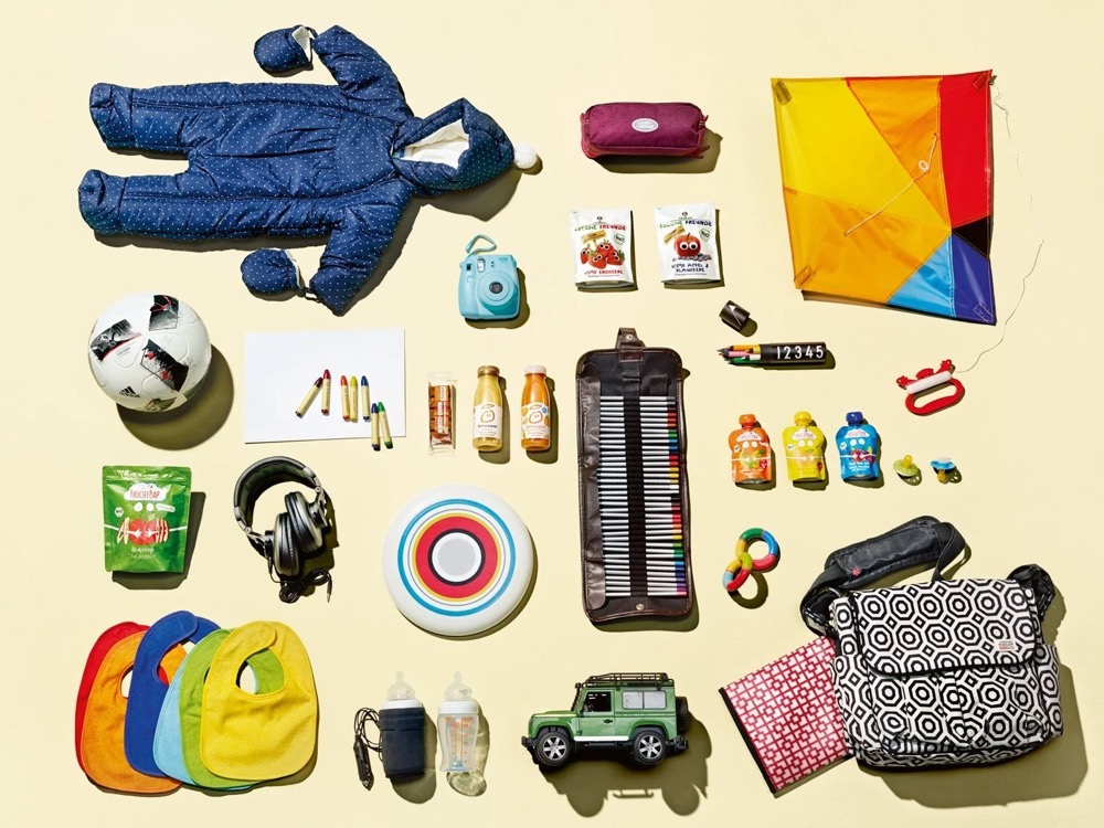 Flatlay für einen Familienausflug mit Schneeanzug, Drachen und Spielzeug, Land Rover Discovery Adventure Series