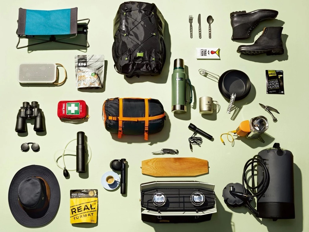 Flatlay mit Campingausrüstung, Rucksack, Fernglas und Stiefeln, Land Rover Discovery Adventure Series