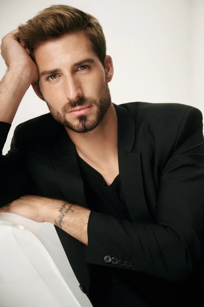 Kevin Trapp im schwarzen Blazer an ein Sofa gelehnt, Kampagne für Merz Aesthetics