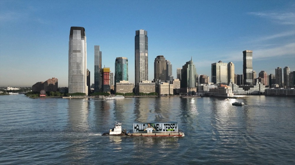 Werbebarge mit „Hallo New Jersey“ auf dem Hudson River vor der Skyline von Jersey City, Nike Football Jamal Musiala WM 2026