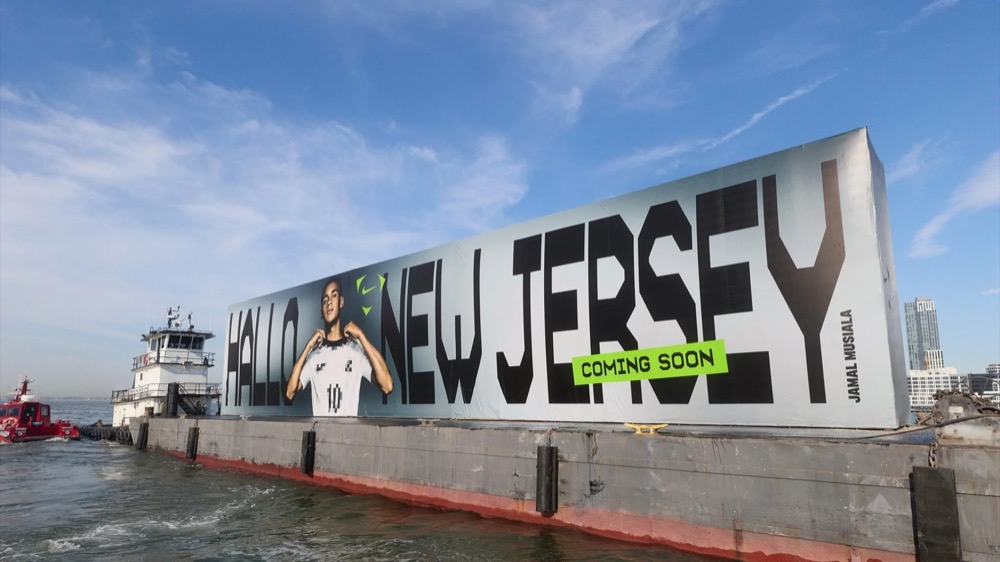 Nahaufnahme des „Hallo New Jersey“-Plakats mit Jamal Musiala auf einer Barge, Nike Football Jamal Musiala WM 2026