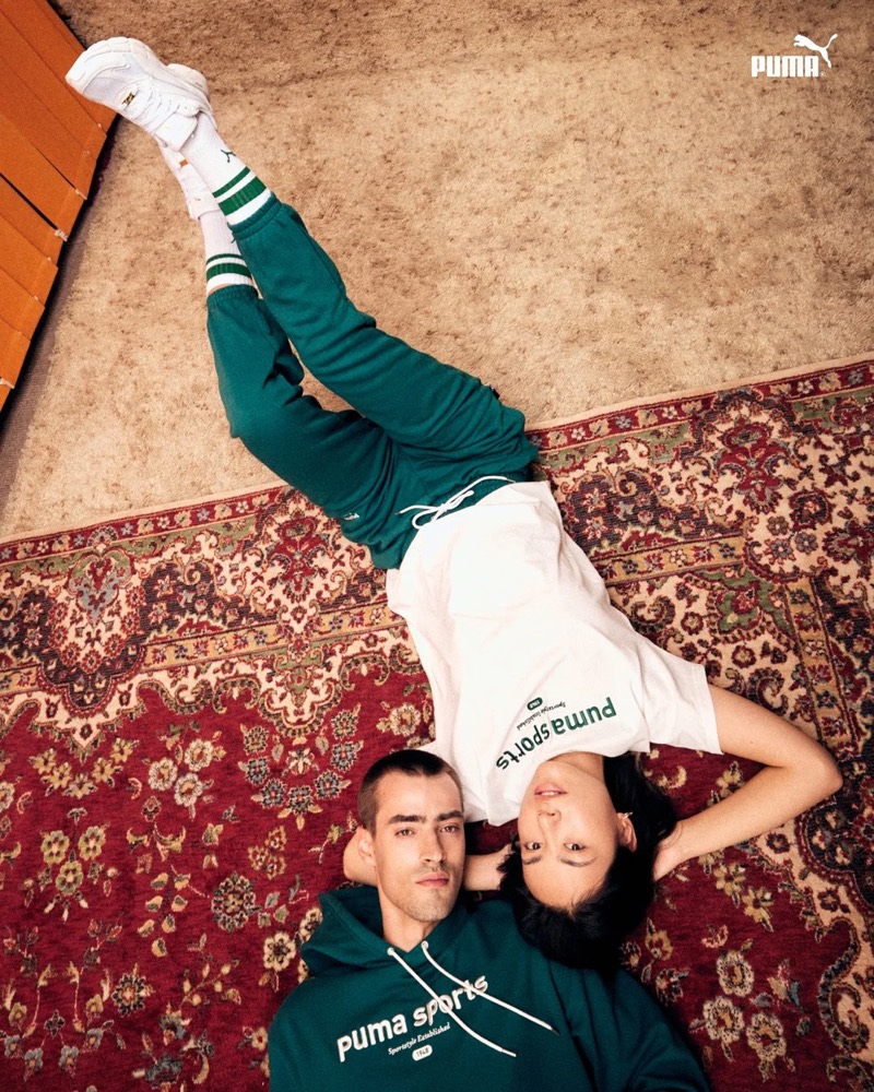 Zwei Models in Puma-Sweatshirts liegen auf einem Teppich, Puma AW23