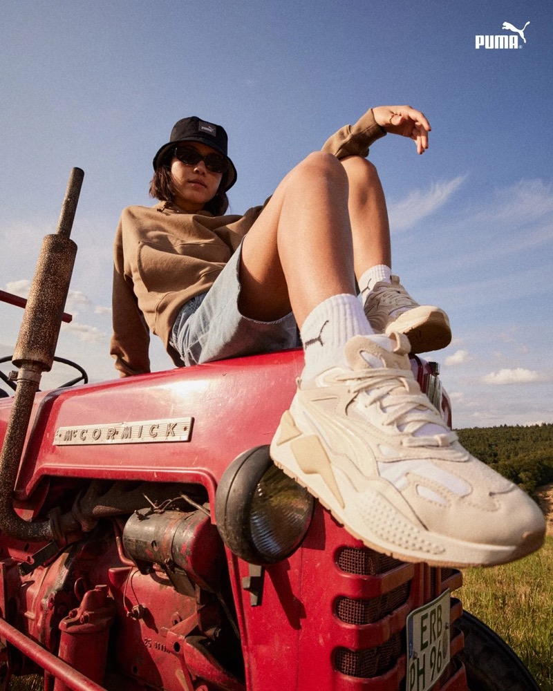 Model in Puma-Sneakern sitzt auf einem roten Traktor, Puma AW23