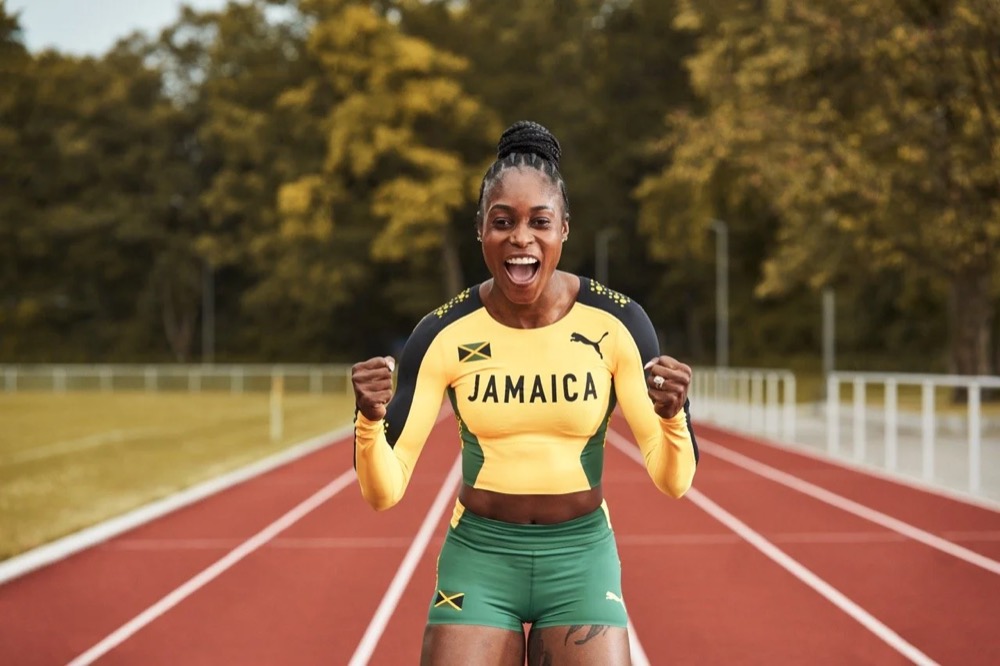 Elaine Thompson-Herah im Jamaika-Trikot auf einer Laufbahn, Puma Fireglow
