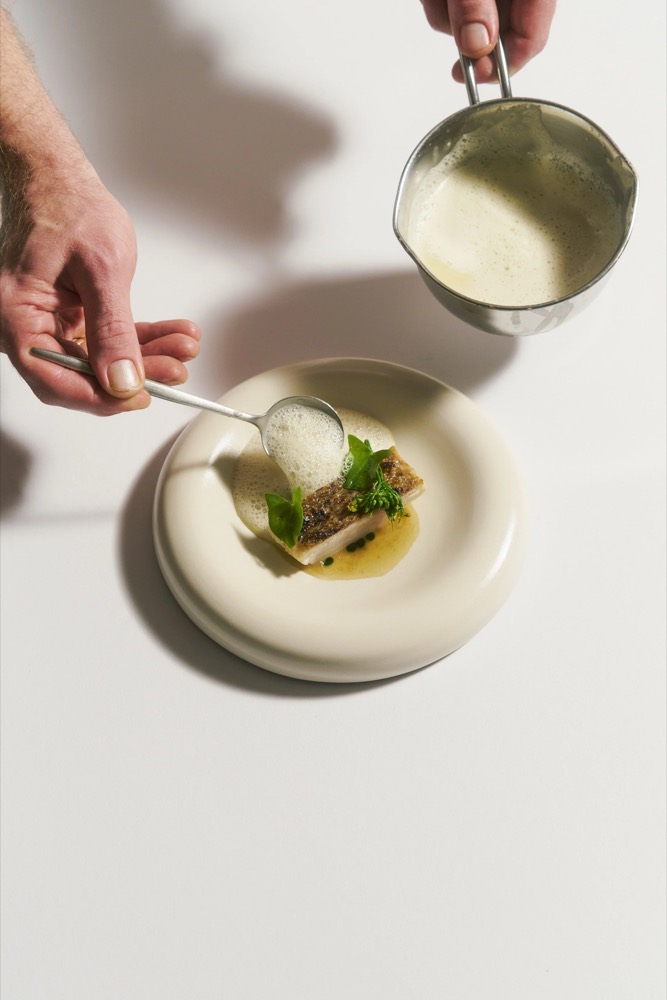 Sauce wird über ein angerichtetes Gericht gegossen, Foodfotografie für das Restaurant Rausch