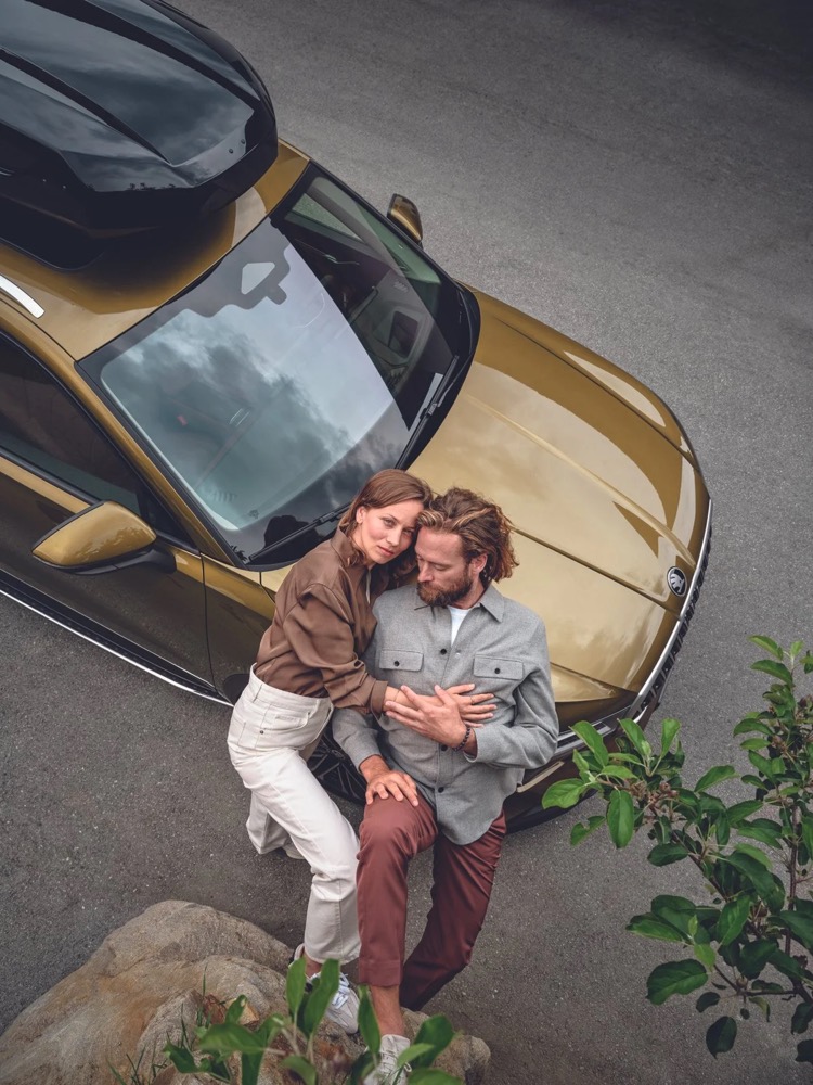 Paar sitzt auf der Motorhaube eines Škoda Kodiaq, von oben, Škoda-Zubehörkampagne