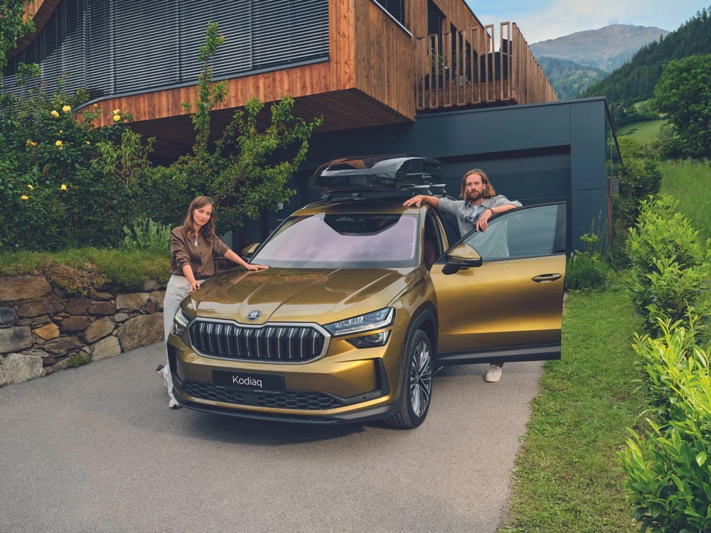 Škoda Kodiaq mit Dachbox vor einem Haus in den Bergen, Škoda-Zubehörkampagne