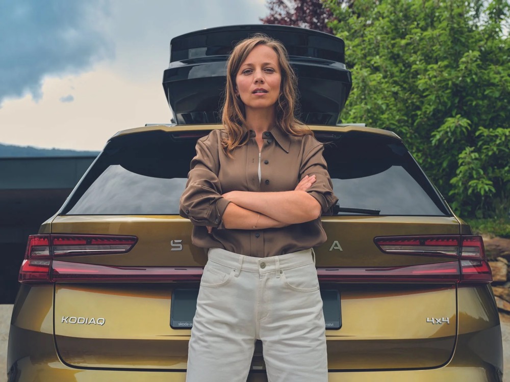 Frau lehnt am Heck eines Škoda Kodiaq mit Dachbox, Škoda-Zubehörkampagne