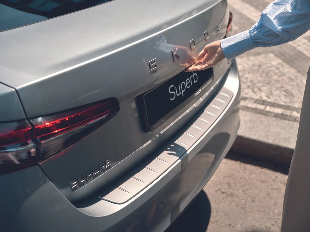 Hand öffnet den Kofferraum eines silbernen Škoda Superb, Škoda-Zubehörkampagne