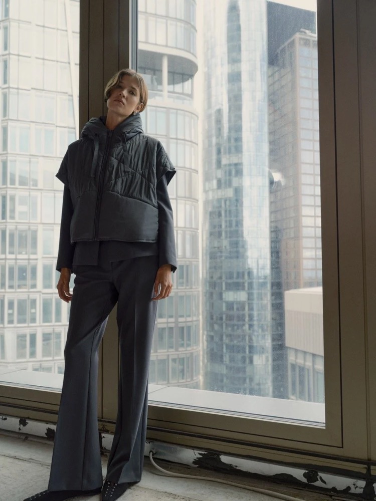 Model in dunkler Steppweste vor einem Hochhausfenster, Fashion-Shooting für someday. in Frankfurt