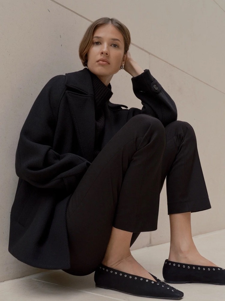 Model im schwarzen Mantel auf dem Boden sitzend, Fashion-Shooting für someday. in Frankfurt