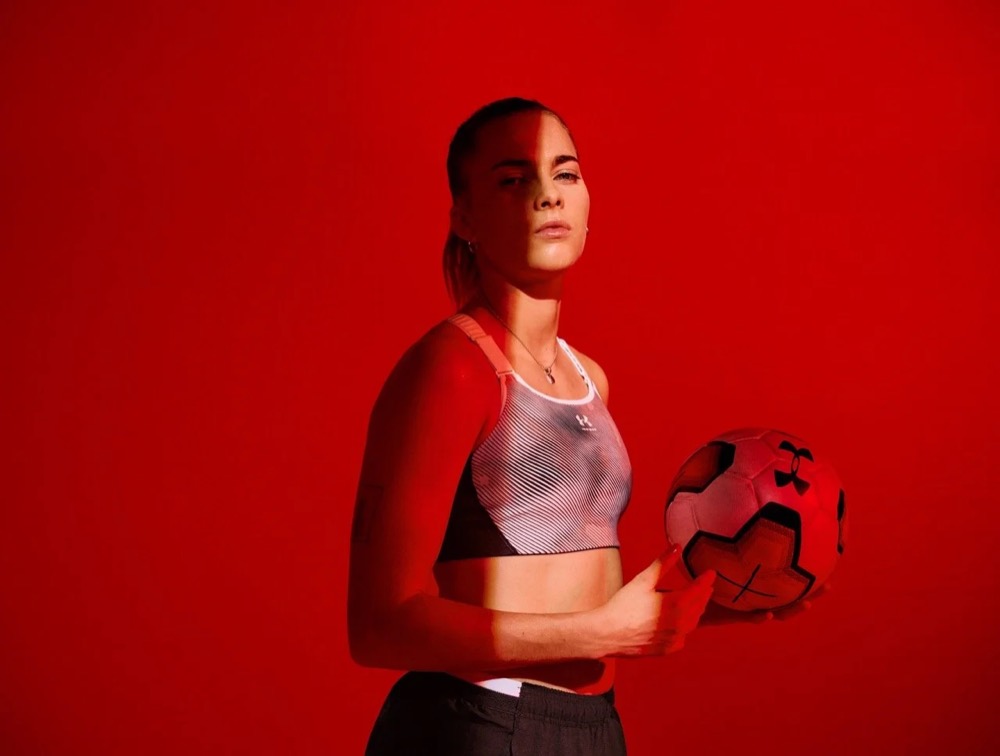 Laura Freigang mit Fußball in einem roten Studio, Under-Armour-Kampagne