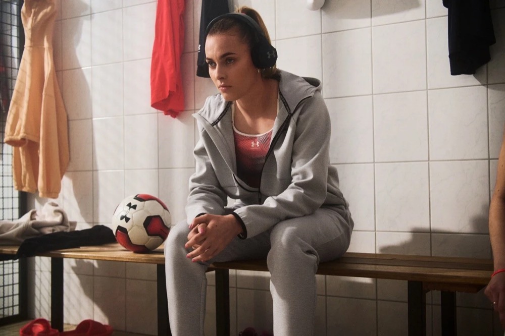 Laura Freigang im grauen Under-Armour-Hoodie auf einer Bank in der Kabine